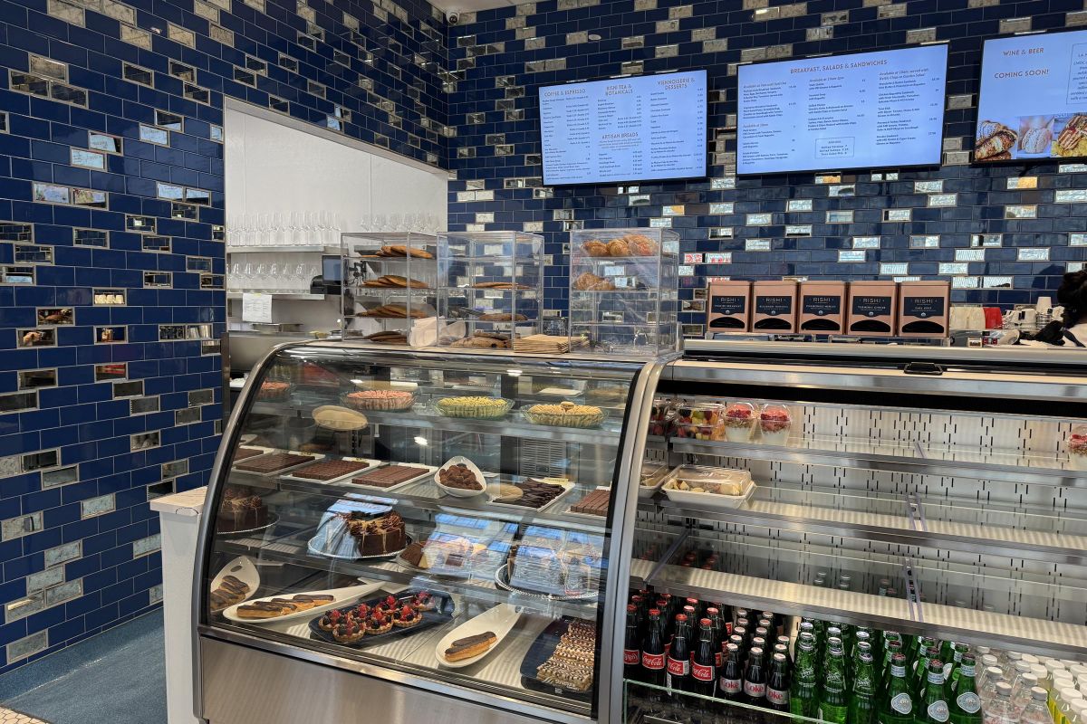 Mother Dough bakery interior counter cooler full of fresh baked goods and beverages, in front of tile wall with large digital menus, Minneapolis MN