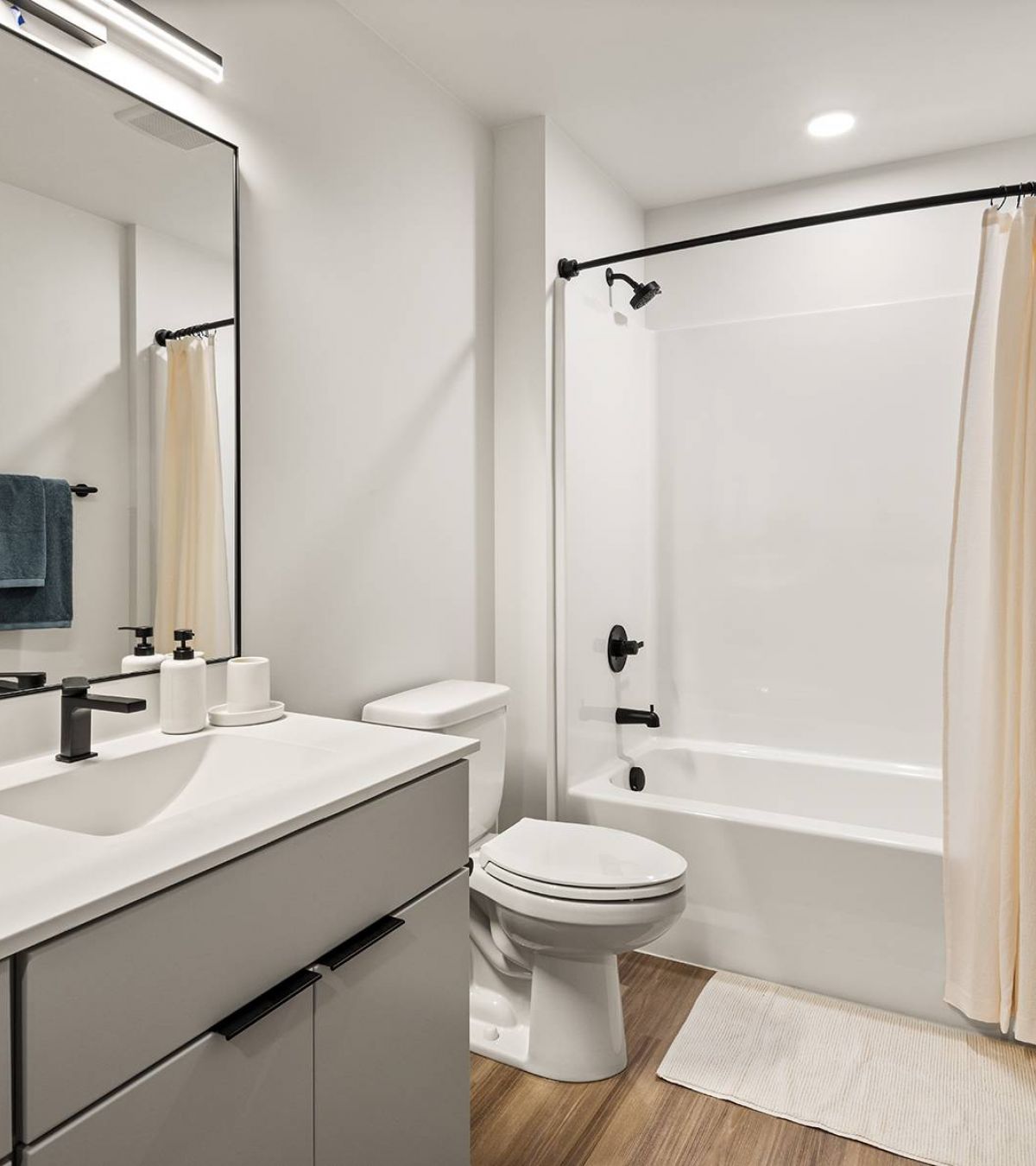 O2 Luxury Towers apartments bathroom with spacious countertop space, cabinets, toilet, and in-shower bathtub.
