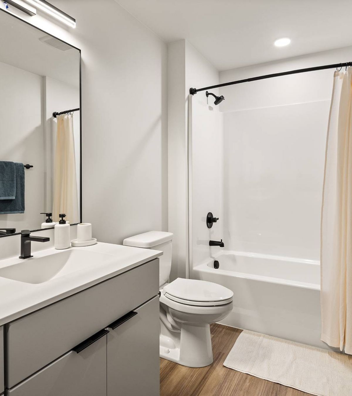 O2 Luxury Towers apartments bathroom with spacious countertop space, cabinets, toilet, and in-shower bathtub. 