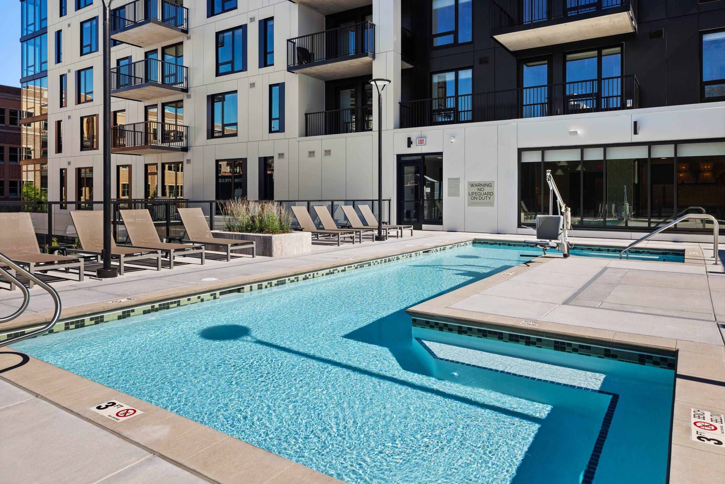 O2 Luxury Towers apartments pool deck amenity on second floor of building with rooftop lounge seating and grilling area.